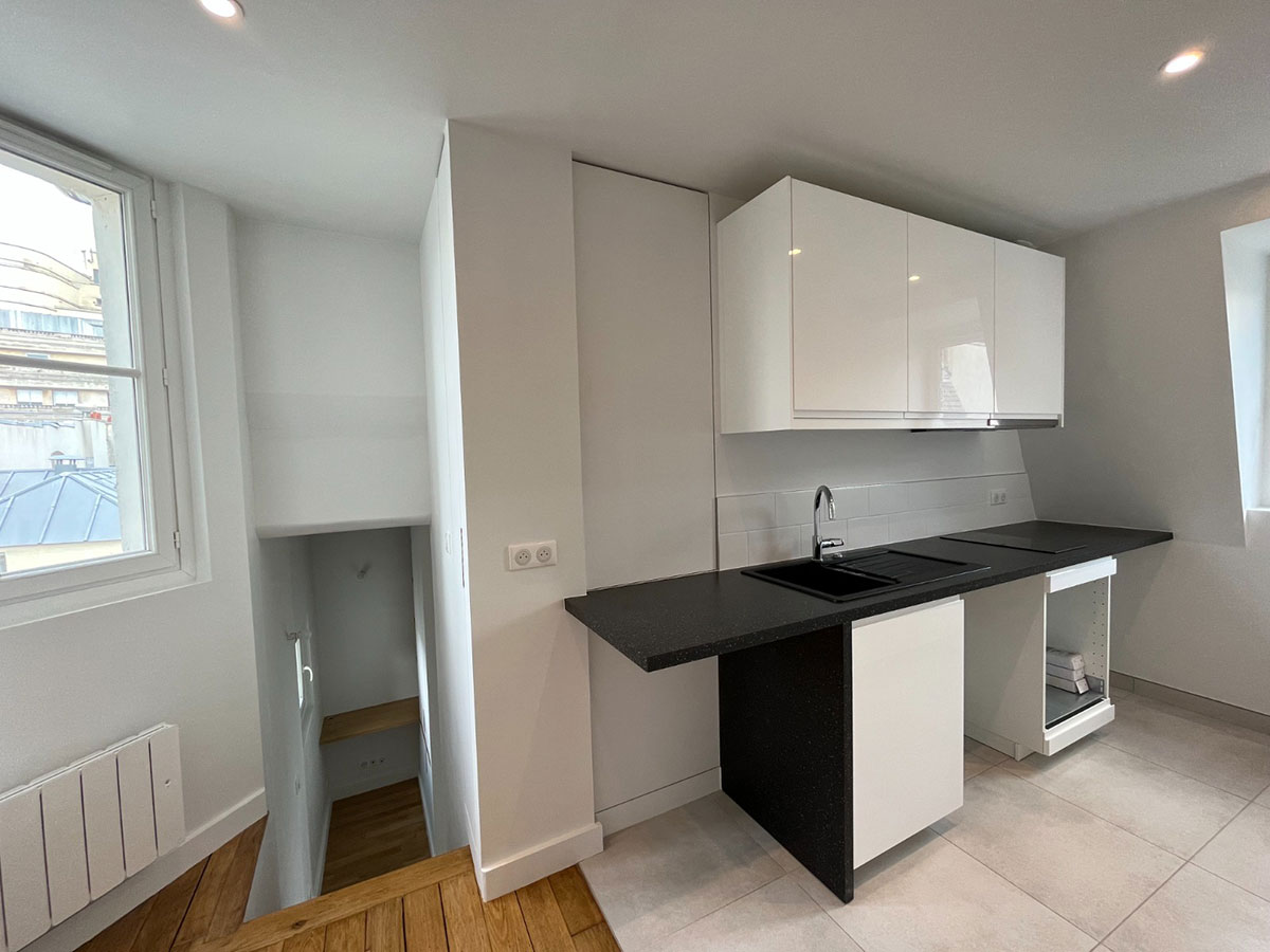 Rénovation de cuisine moderne blanche avec plan de travail noir réalisée à Paris par TEOBAT